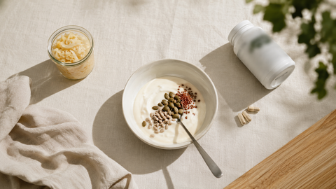Bol de yogur natural con semillas, chucrut en tarro de cristal y cápsulas de probióticos sobre mantel de lino